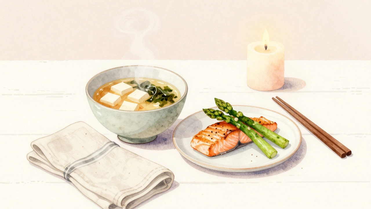 Miso soup with tofu and asparagus beside grilled salmon at a quiet dinner table